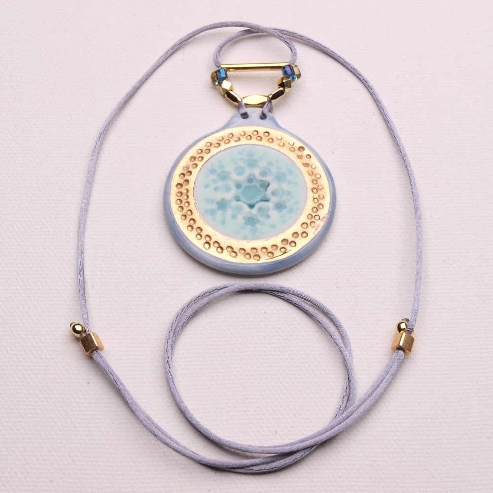 Eine Schneeflocken-Halskette aus Keramikporzellan mit einem funkelnden 24-karätigen Goldglanzband und einem verstellbaren Schlüsselband. Ein ideales modisches Accessoire für den Winter.