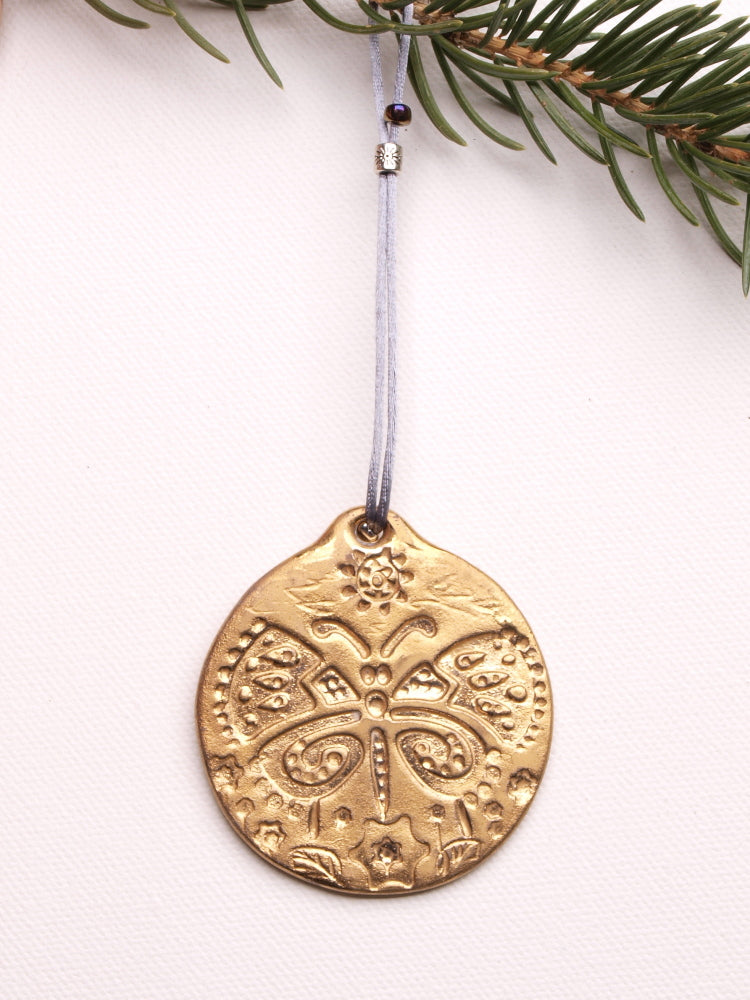 A ceramic collectable tree ornament with a golden butterfly pattern. @ 2in dia., .15in thick