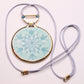 A ceramic porcelain snowflake pendant necklace, with a sparkling gold luster band, adjustable lanyard.